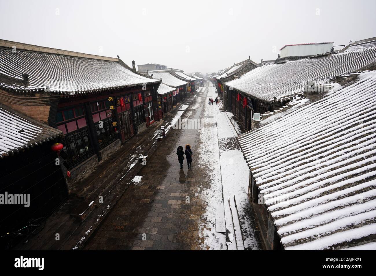 Pingyao, China. 5 de enero, 2020. Los turistas visitan nevados Pingyao Antigua ciudad en el norte de la Provincia china de Shanxi, 5 de enero de 2020. Fundada en el siglo 14, la antigua ciudad de Pingyao es un ejemplo excepcionalmente bien conservado de una ciudad chinos tradicionales, que fue nombrada Patrimonio de la Humanidad por la UNESCO en 1997. Crédito: Zhan Yan/Xinhua/Alamy Live News Foto de stock