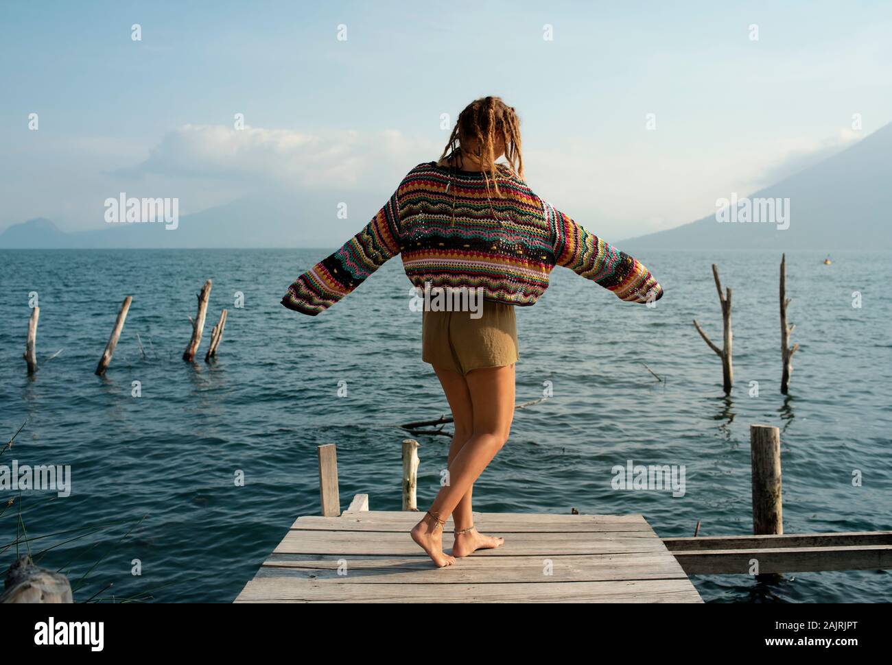 Vista trasera de la atractiva mujer caucásica bailando en un embarcadero. Estilo de vida al aire libre, viaje, vacaciones, solo concepto recreativo. Lago Atitlán, Guatemala Foto de stock