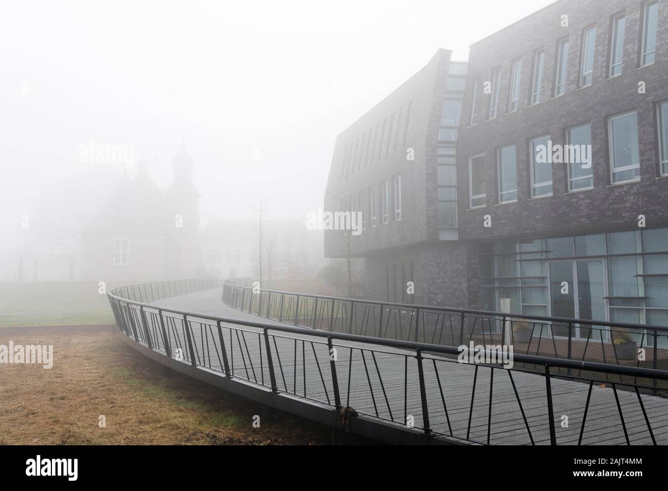 Ayuntamiento de Coevorden, Países Bajos, en la bruma con castillo histórico apenas visible en el fondo Foto de stock