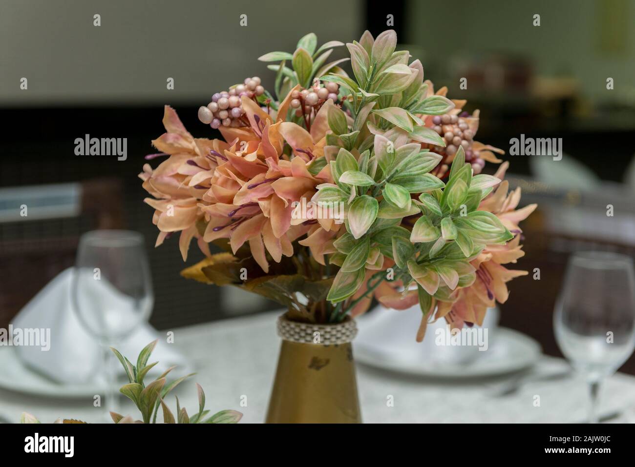 Los cuencos de cristal, servilletas de tela y flores decorativas en hermoso jarrón sobre una mesa de comedor junto a una vela. Decoración sencilla de aniversario de boda. T Foto de stock