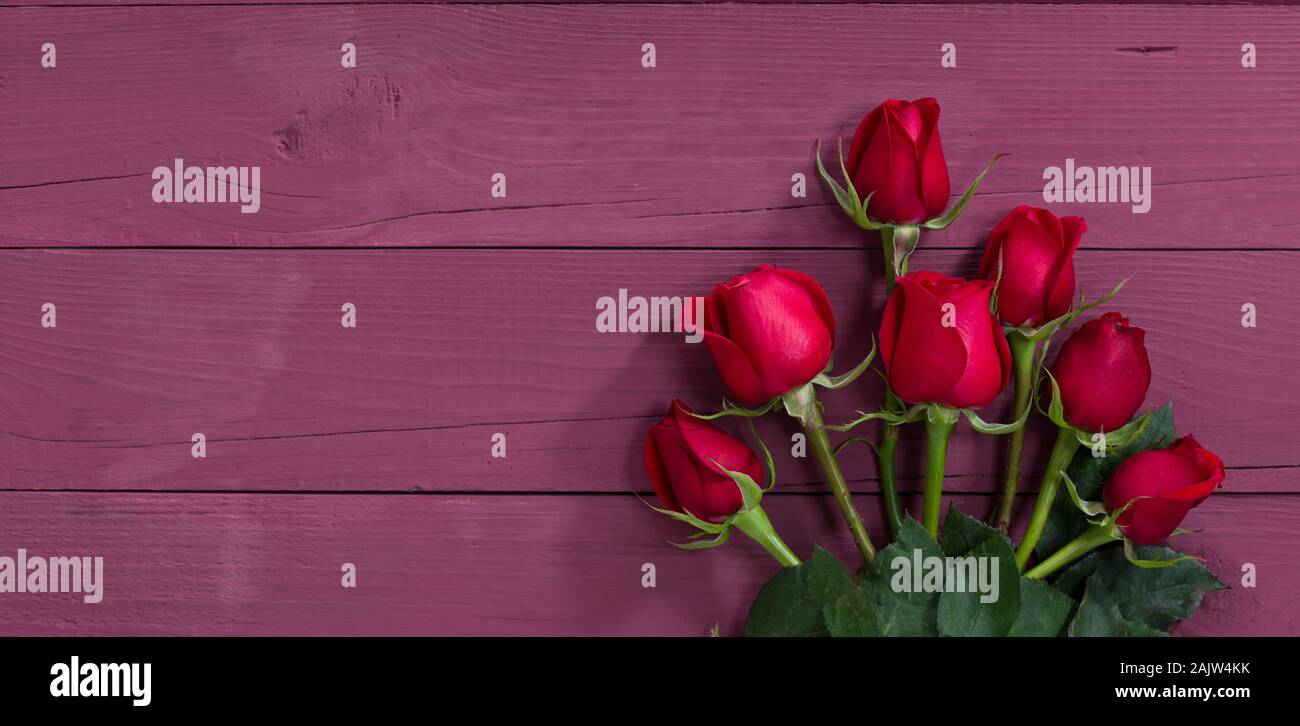 Tarjeta del Día de San Valentín. Caja de regalo roja y rosas sobre púrpura mesa de madera Foto de stock