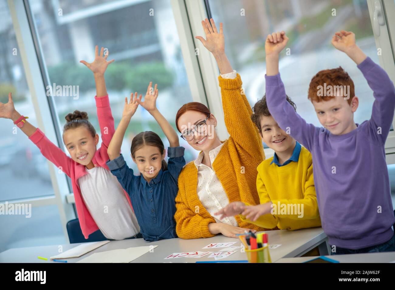 Maestros y Niños levantando las manos arriba en la clase Foto de stock