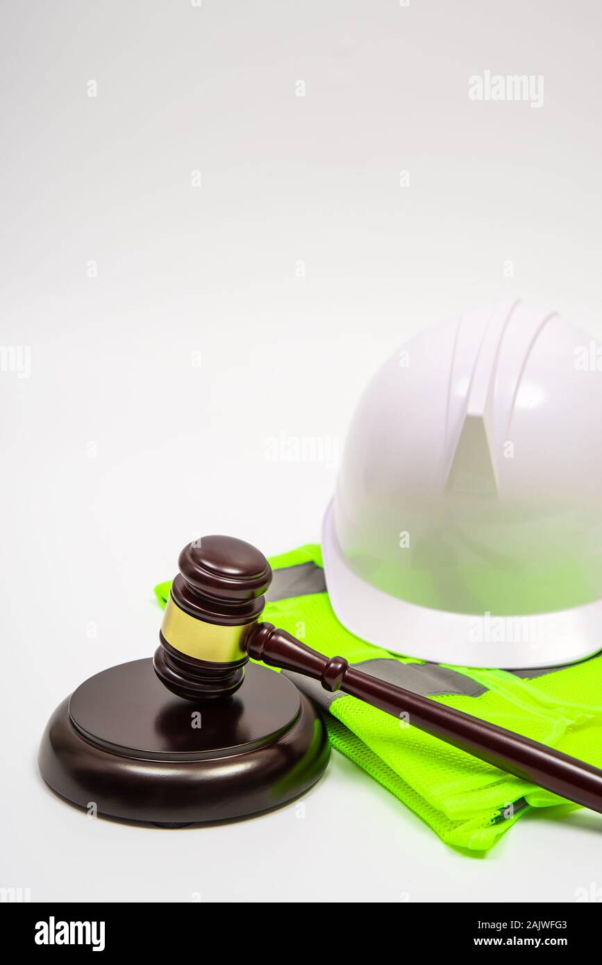 Un concepto jurídico laboral con seguridad sombreros, ropa de trabajo, y un juez martillo sobre un fondo blanco. Foto de stock