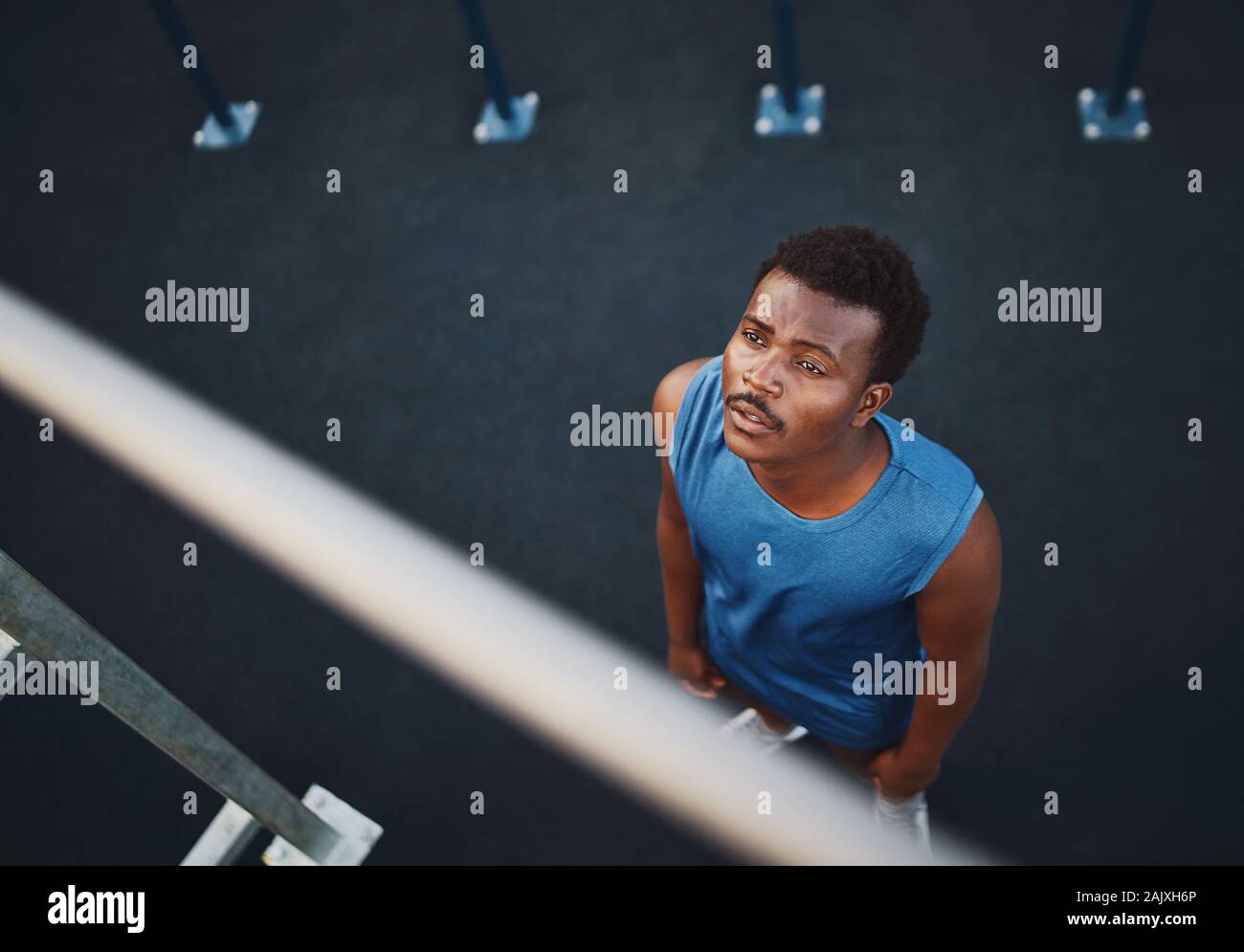 Una vista aérea de un joven afroamericano atleta masculino se prepara para hacer tirar ups en la barra horizontal - el hombre asustado de ejercicio Foto de stock
