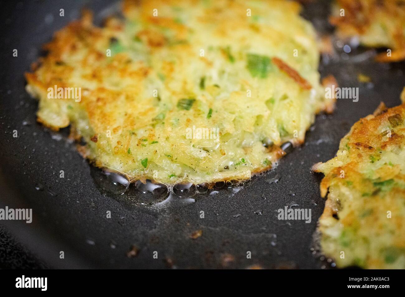 Primer plano de panqueques de patata fritos en una sartén de aceite caliente Foto de stock