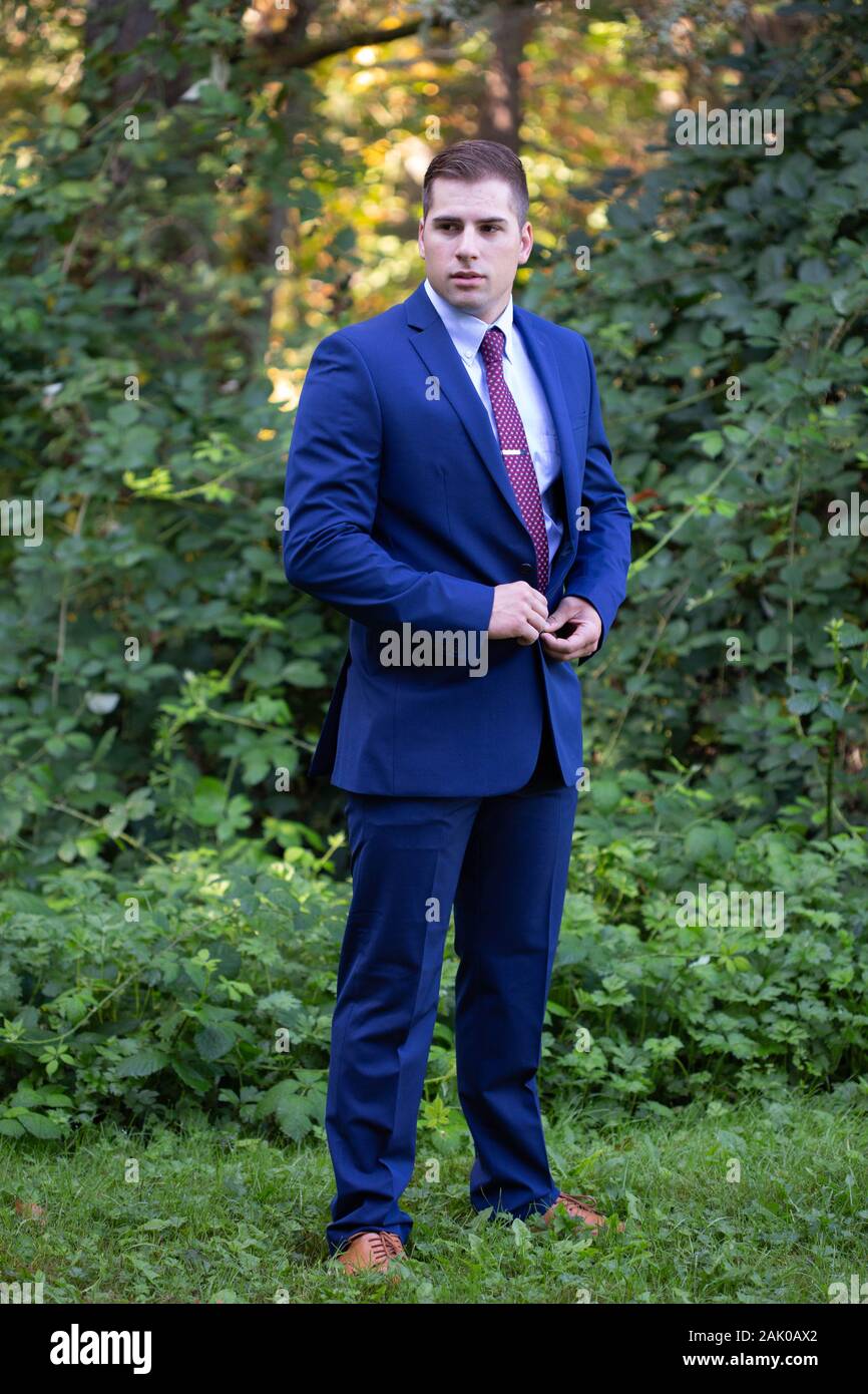 Hombre joven serio en traje se para fuera y botones chaqueta Fotografía de  stock - Alamy
