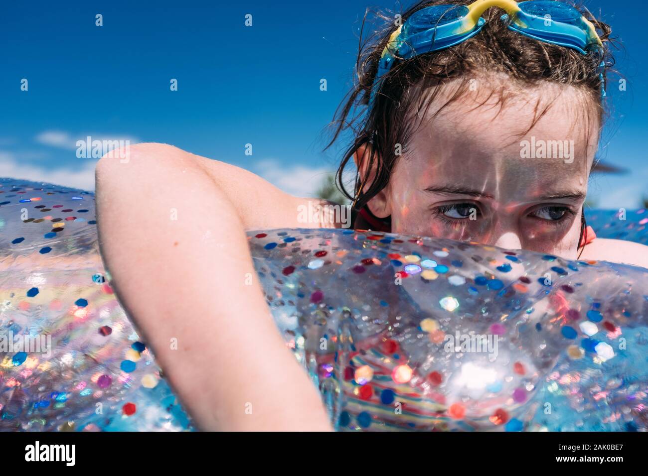 primer plano de una chica triste que parece flotar en la piscina con gafas en la cabeza Foto de stock