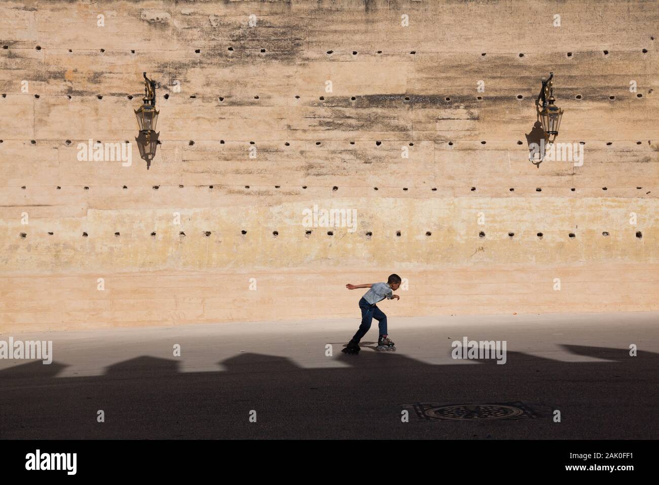 Un niño patinando por la tarde el paisaje de las murallas de la ciudad en Fez (Fez) cerca de Bab Mechuar y Bab Dekkakin Foto de stock