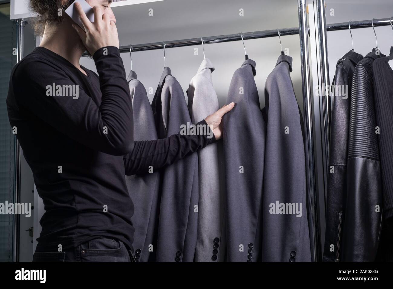 Suave golondrina Tomar medicina Close-up retrato de un hombre joven con barba, milenario, en una tienda de ropa  para hombres, elige un traje de negocios para trabajar, hablando en un  smartphone, consulta o Fotografía de stock -