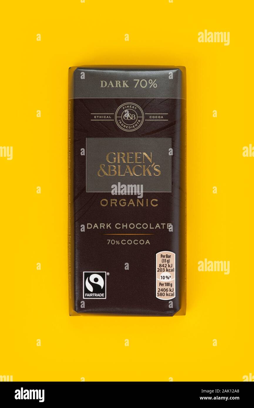 Una barra de color verde y negro de la filmación de chocolate oscuro sobre un fondo amarillo. Foto de stock