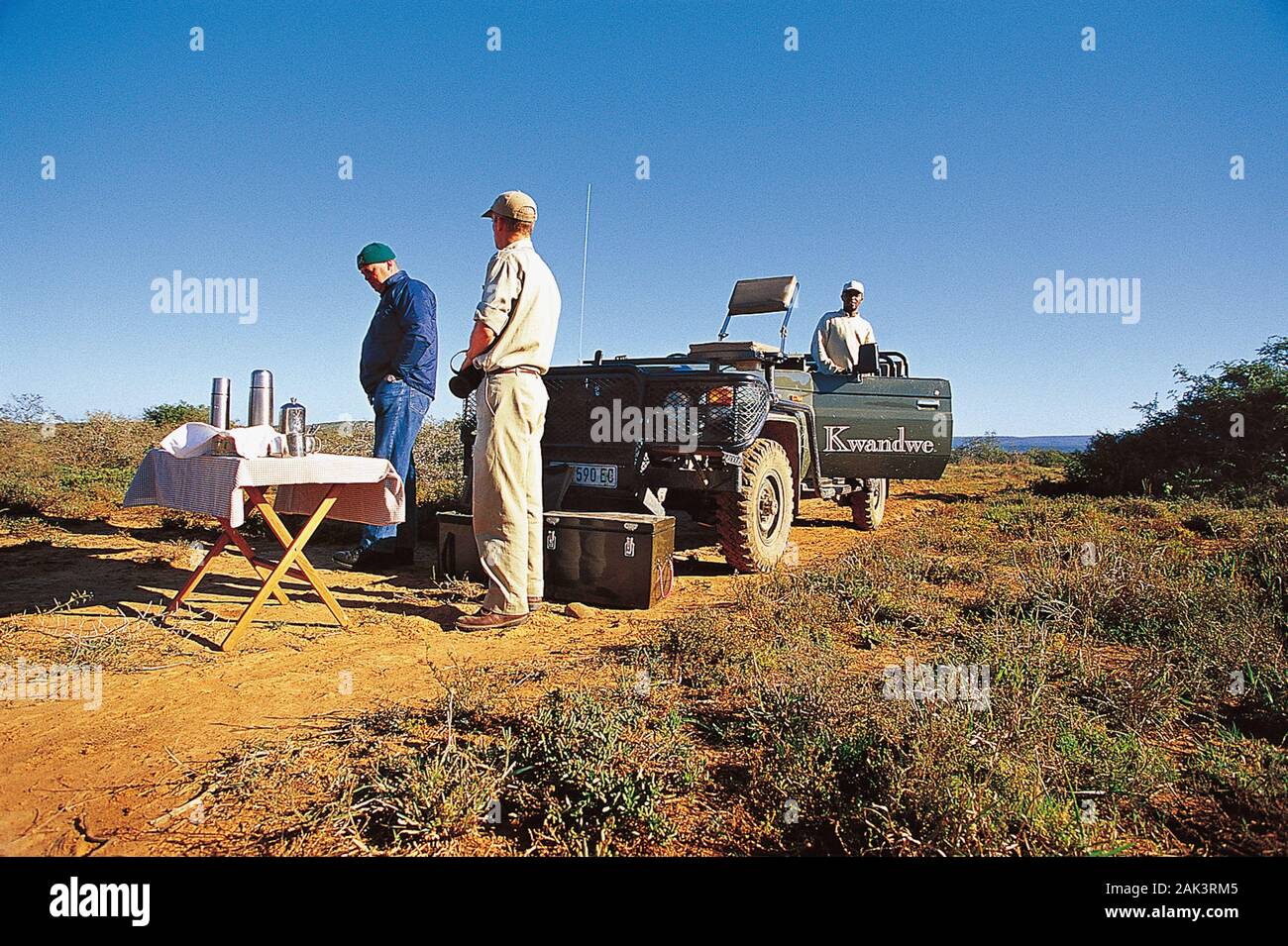 Tres hombres en un picnic romper durante un viaje a través de la safari Kwandwe Private Game Reserve en Eastern Cape en Sudáfrica. (Sin fecha) | Imagen Foto de stock
