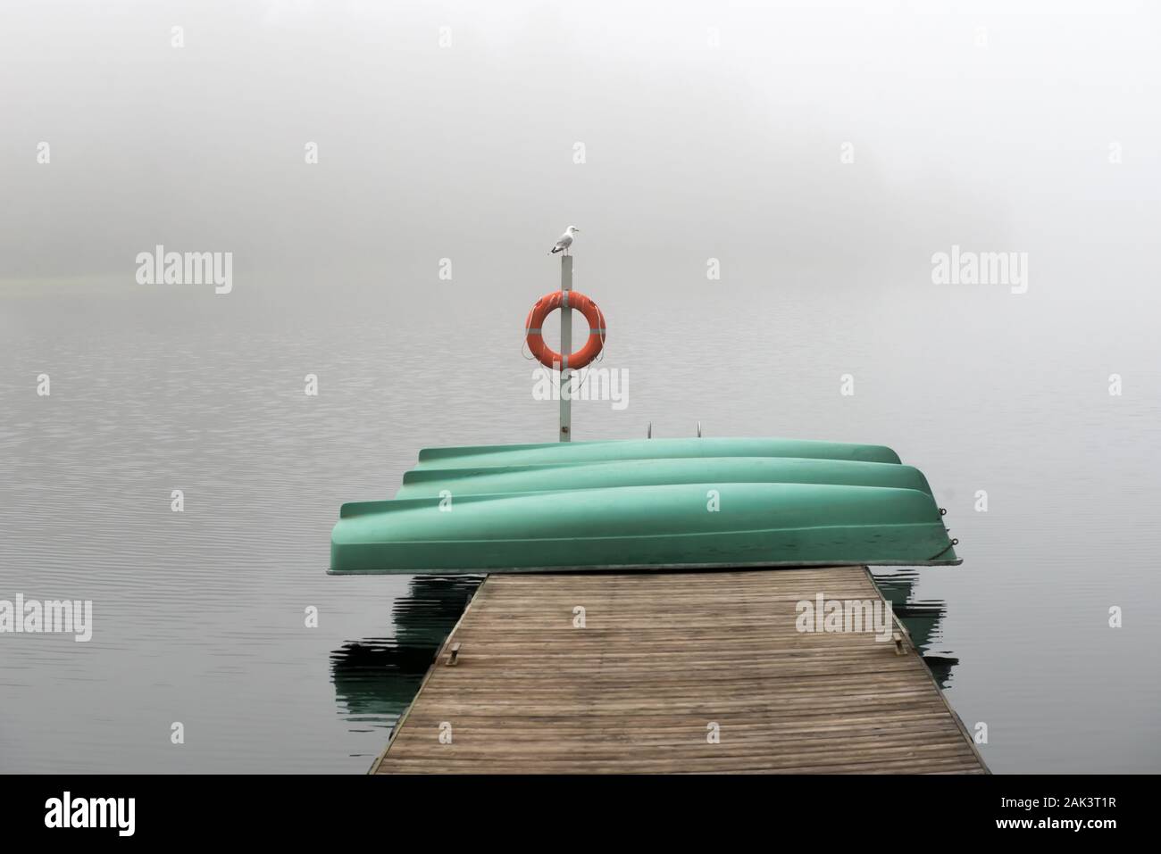 Botes de remo al revés y apilados en un muelle en una mañana de niebla  Fotografía de stock - Alamy
