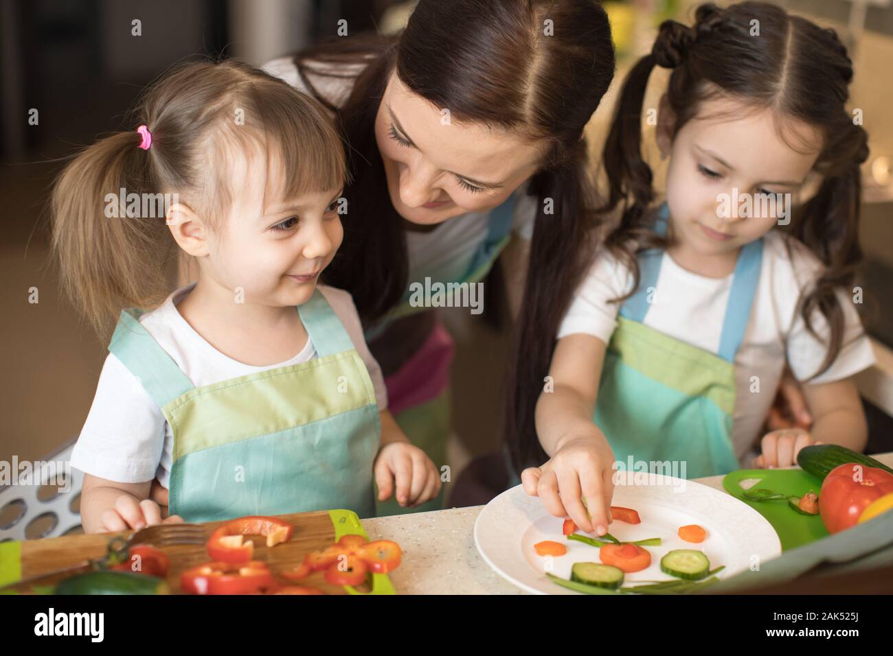 Feliz mamá y sus hijos hijas disfrutar de hacer una comida saludable en su cocina Foto de stock