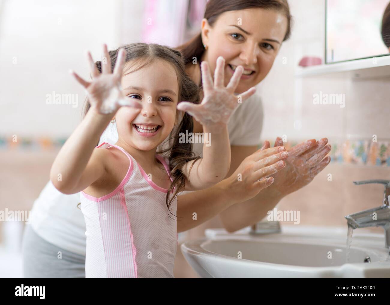 Alegre kid lavarse las manos con jabón y mostrando las palmas Foto de stock