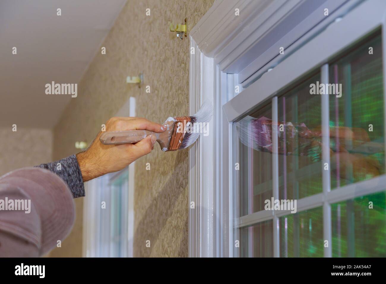 Trabajador de marco de ventana de madera pintura en casa con Paintbrush Foto de stock