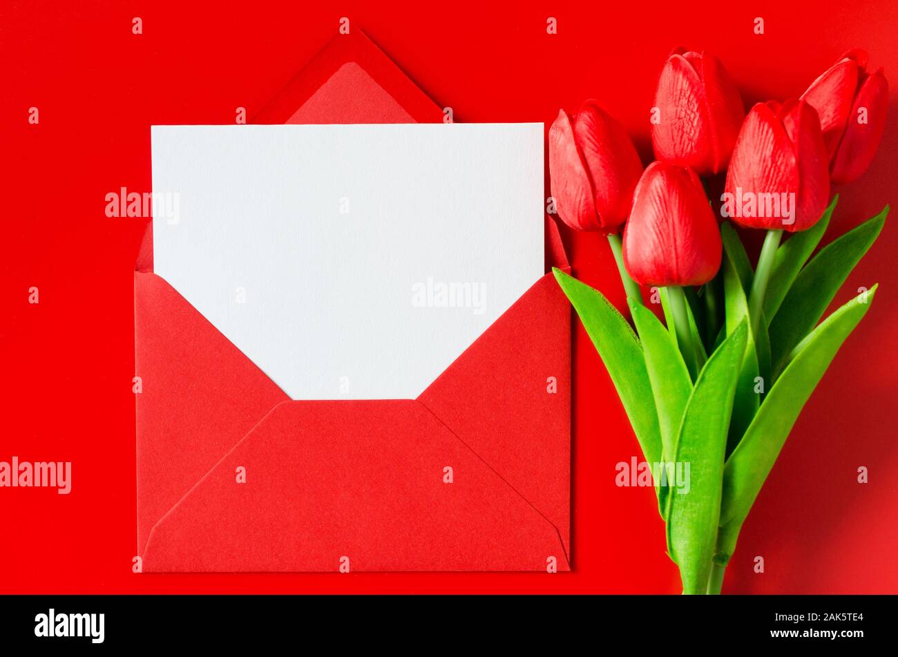 Tarjeta de felicitación para el Día de San Valentín, Día de la mujer o el  día de la madre. Sobres rojos con papel blanco y Ramo de tulipanes. Vista  superior con espacio