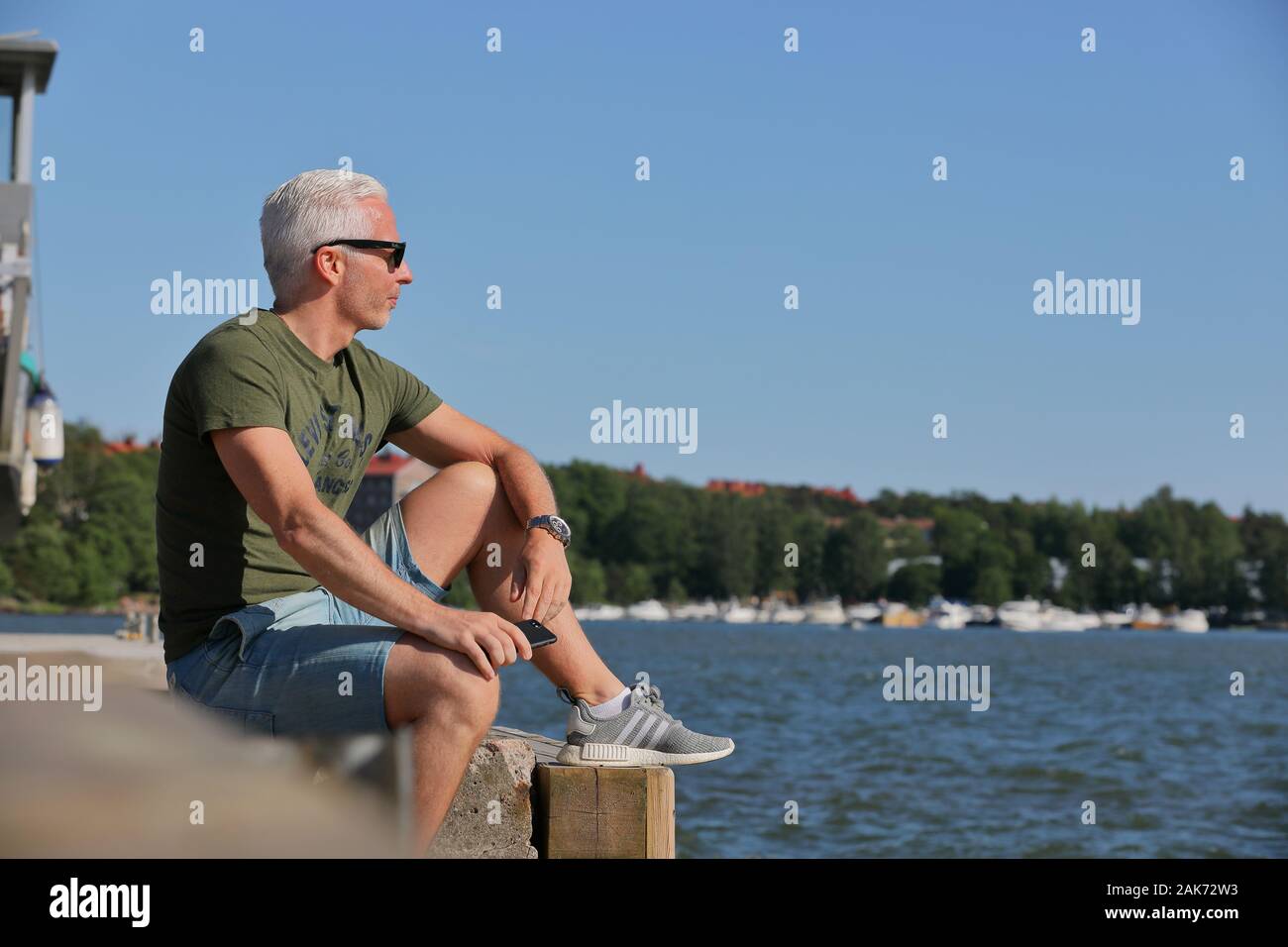 Una persona de sexo masculino con gafas de sol disfrutando de Finés midsummer por mar en la capital finlandesa Helsinki Foto de stock