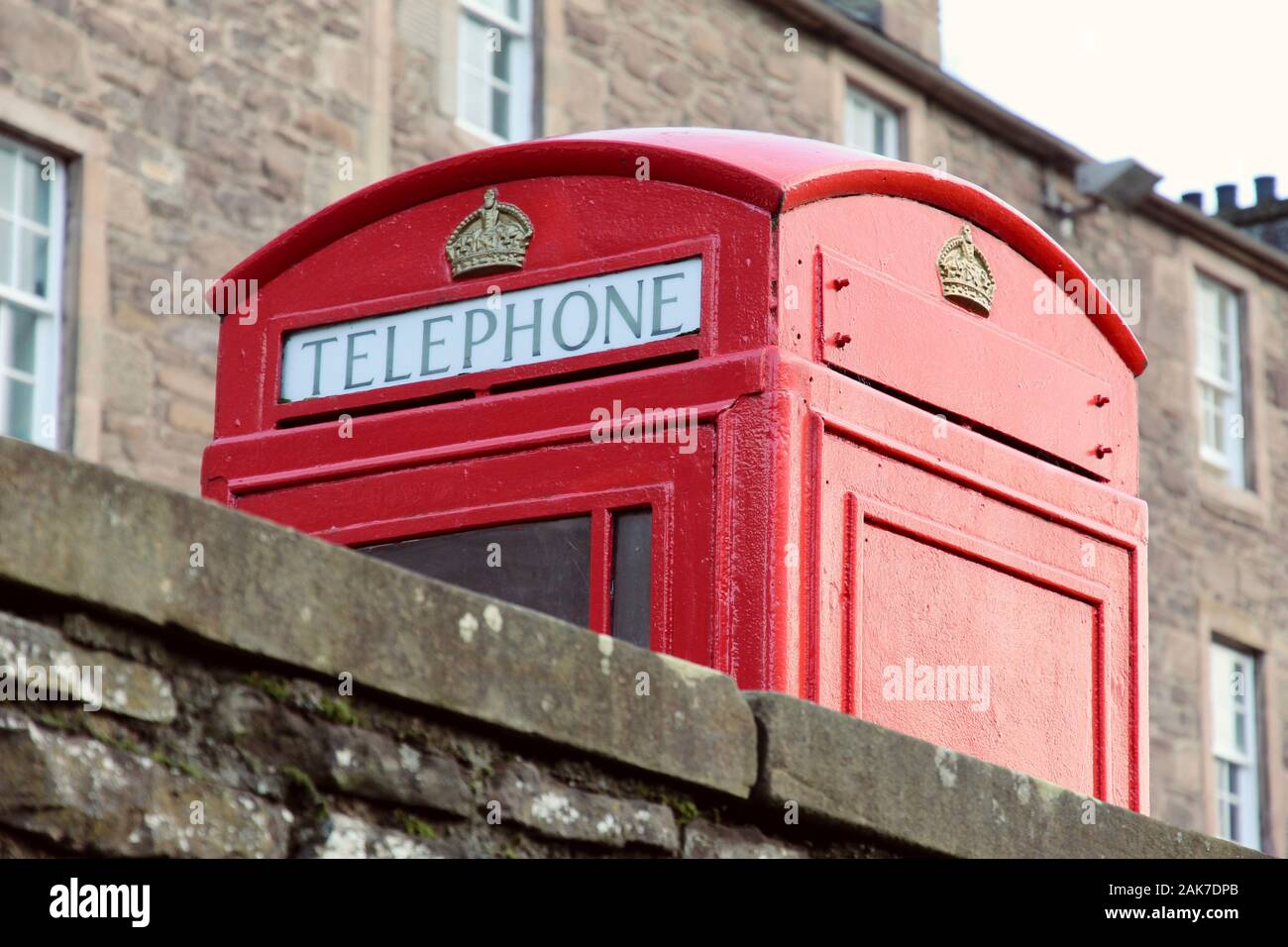 Rojo tradicional cuadro teléfono británico detrás de un muro de piedra en tenement edificio antecedentes Foto de stock
