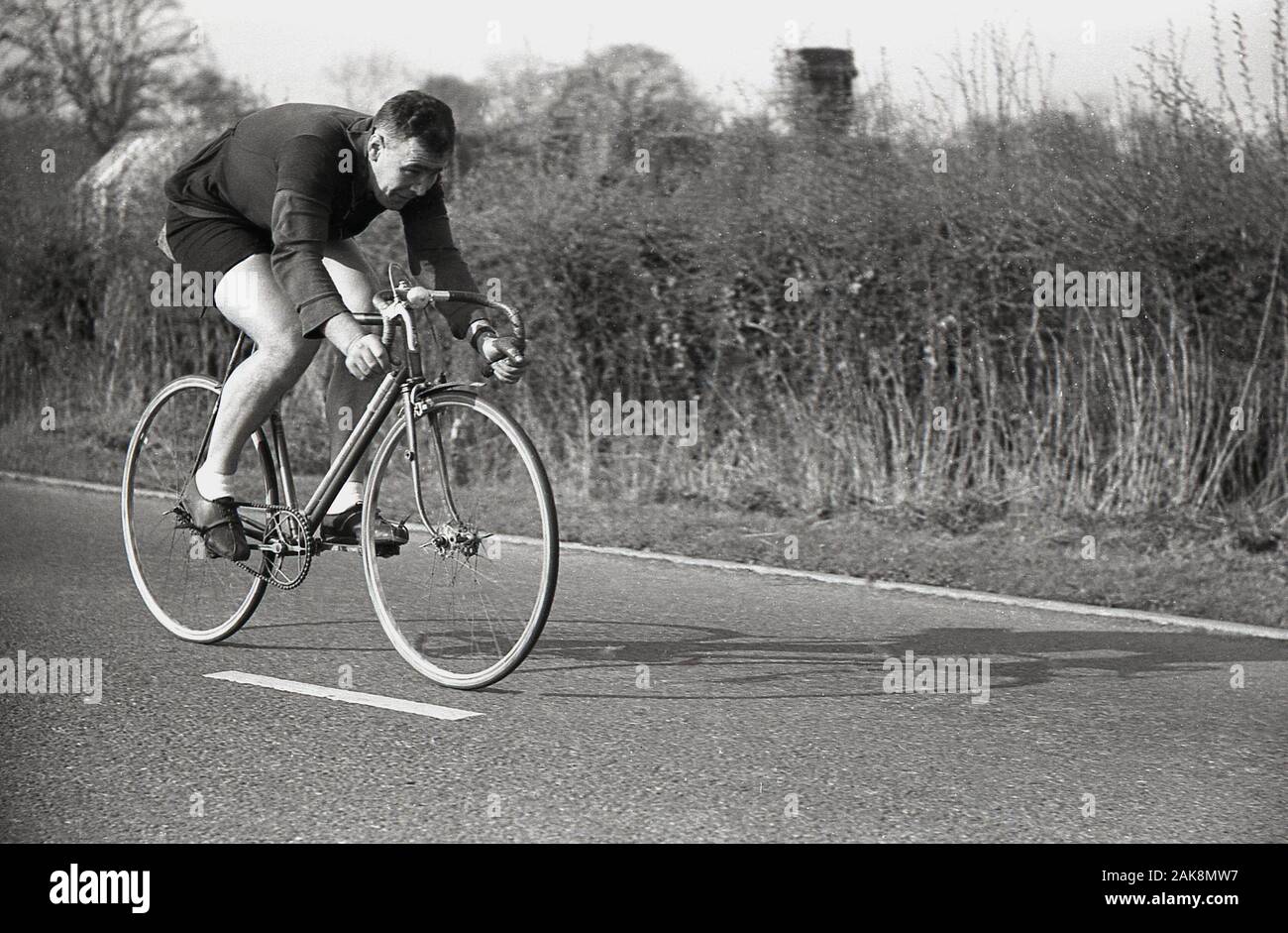 1950, histórica, un macho de contrarreloj El ciclista circulaba en una carretera pública vistiendo la ropa del ciclo de la época, Inglaterra, Reino Unido. Foto de stock