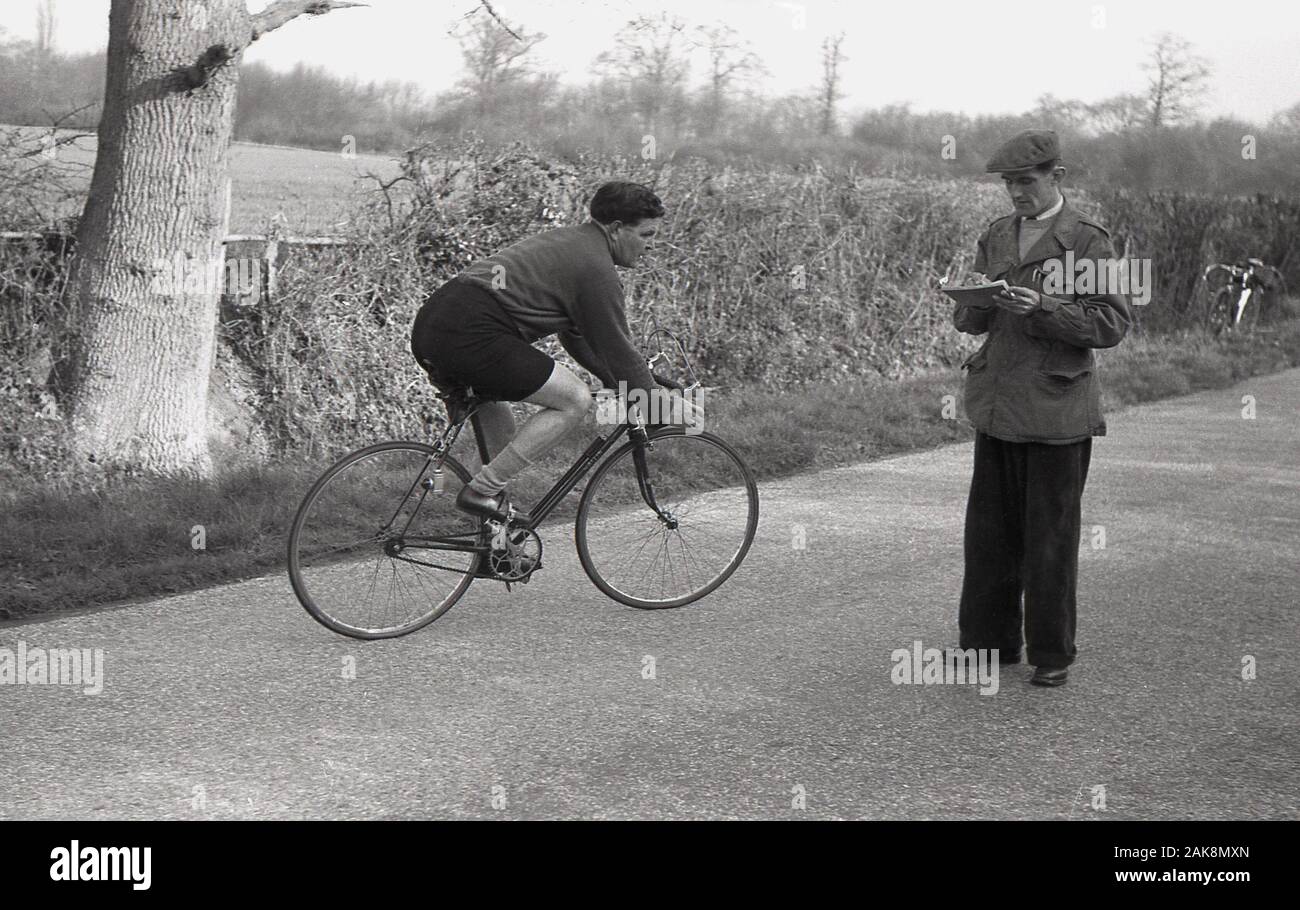 1950, histórica, un macho de contrarreloj ciclista vistiendo la ropa de ciclismo de la época, haciendo una vuelta alrededor de una carrera voluntaria o marshall, Inglaterra, Reino Unido. Foto de stock