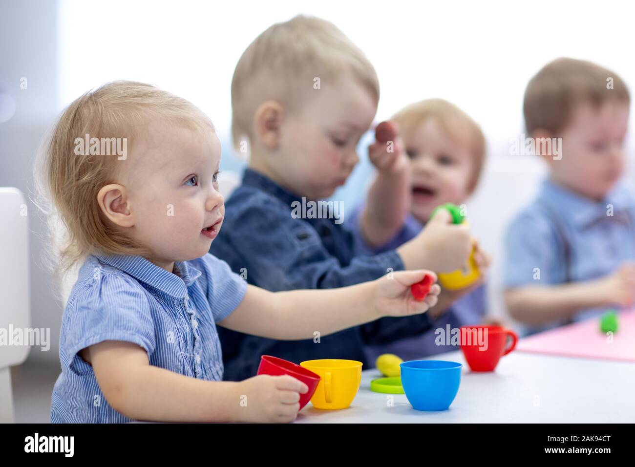 Grupo de niños jugando con jugar la arcilla en la guardería o jardín de infancia o escuela primaria Foto de stock