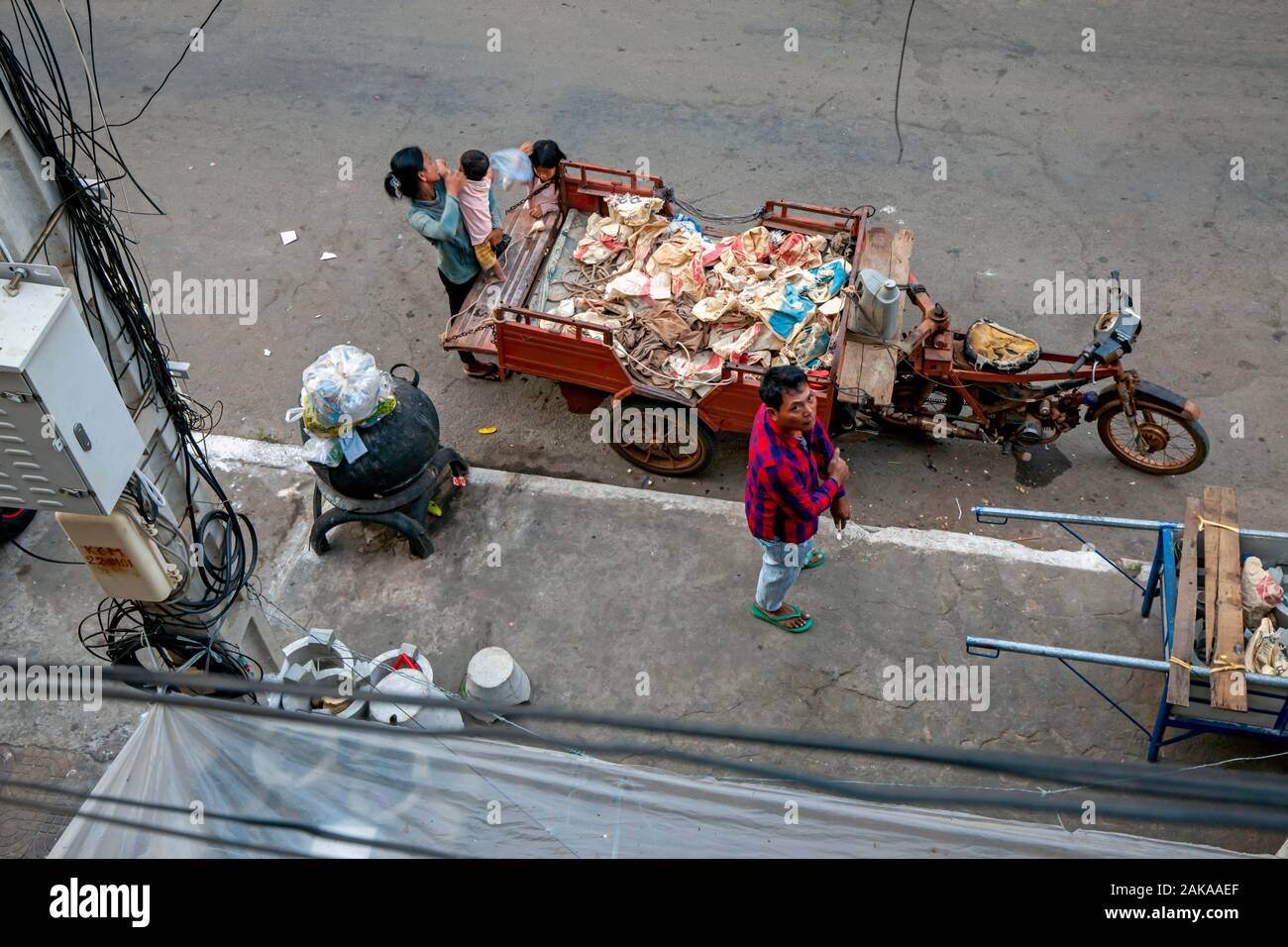 Un hogar pobre scavenger familia está reunida alrededor de un vehículo utilizado para el transporte de material reciclable en una calle de la ciudad de Kampong Cham, Camboya. Foto de stock