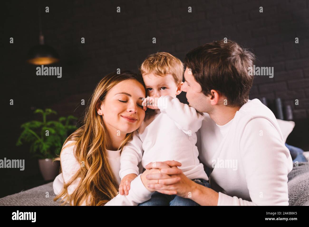 Feliz familia divirtiéndose acostada en la cama, en su casa. Familia feliz en la cama. Papá, mamá e hijo residen en dormitorio en puertas. padre, madre y niño Foto de stock
