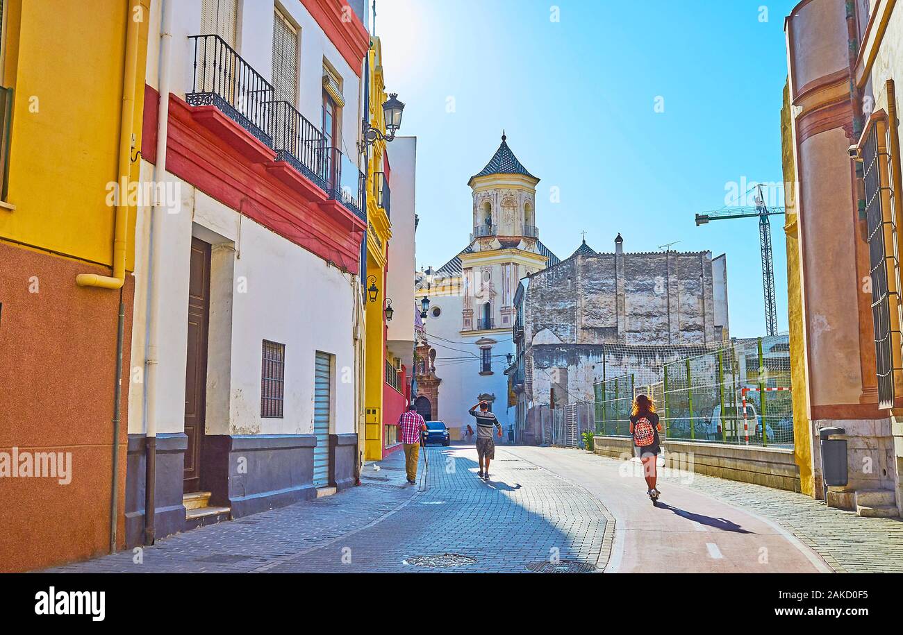 Ver el paisaje urbano de Calle Parras en el casco antiguo de la ciudad con una vista de alto campanario medieval de la Iglesia de San Felipe Neri, Málaga, España Foto de stock