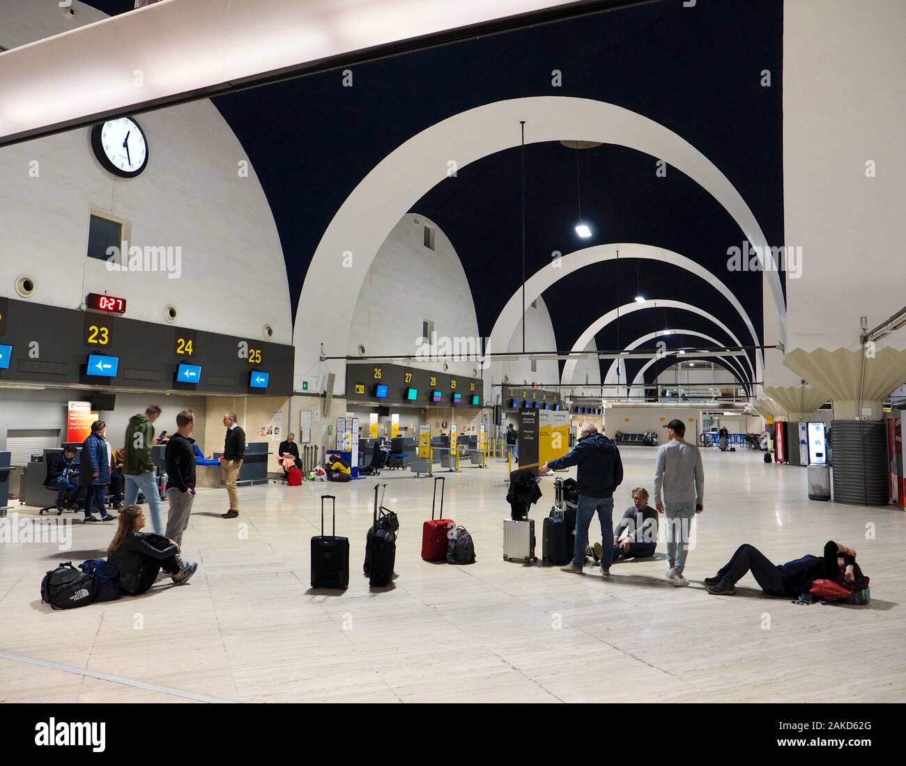 Personas que esperan tarde por la noche en su vuelo retrasado en la terminal del aeropuerto de Sevilla, Andalucía, España Foto de stock