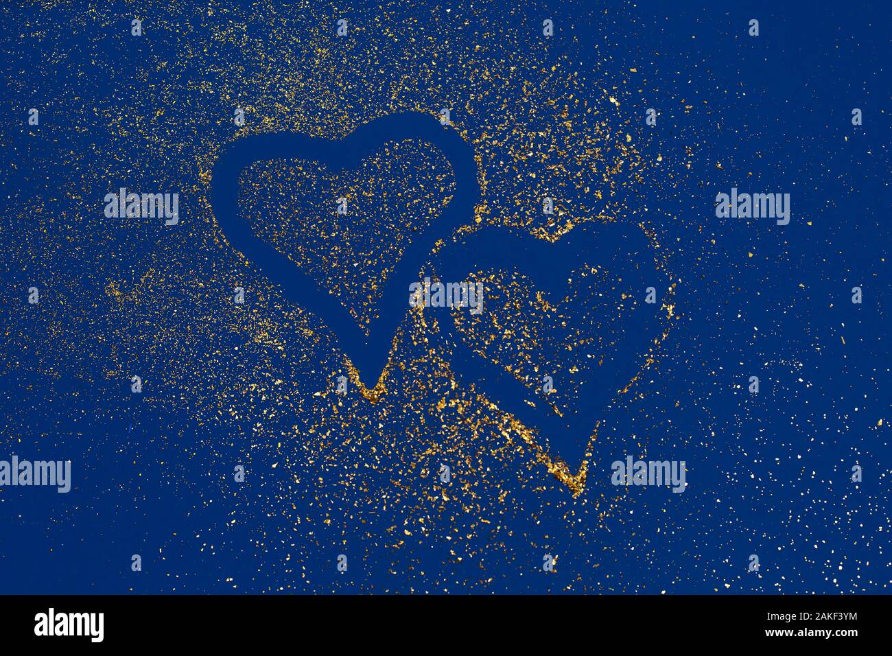Dos corazones de lentejuelas de oro sobre fondo de tendencia azul. Día de San Valentín, el amor concepto. oncept de color de 2020. Tendencia principal del año. Foto de stock