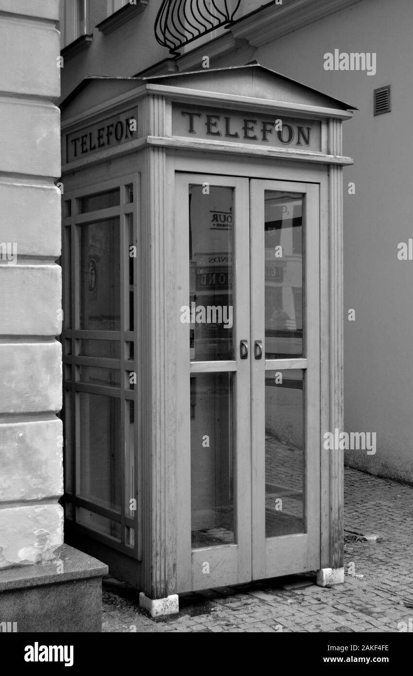 Antiguo puesto de teléfono blanco y negro que adorna las calles antiguas de la ciudad Foto de stock