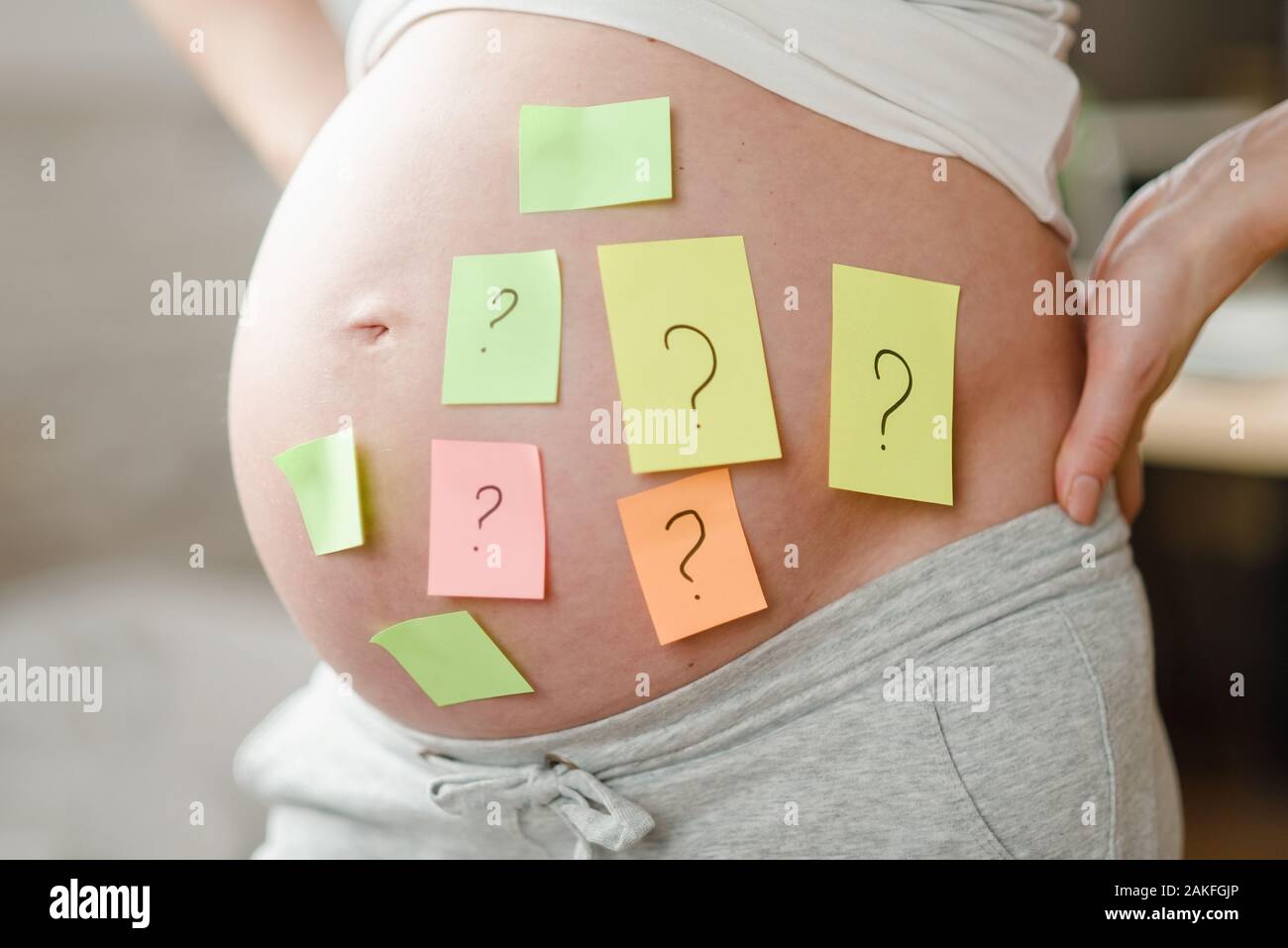 Concepto de escoger el nombre del bebé. Recorta foto de mujer embarazada  con signos de interrogación en papel pegatinas sobre el estómago, cerca  Fotografía de stock - Alamy