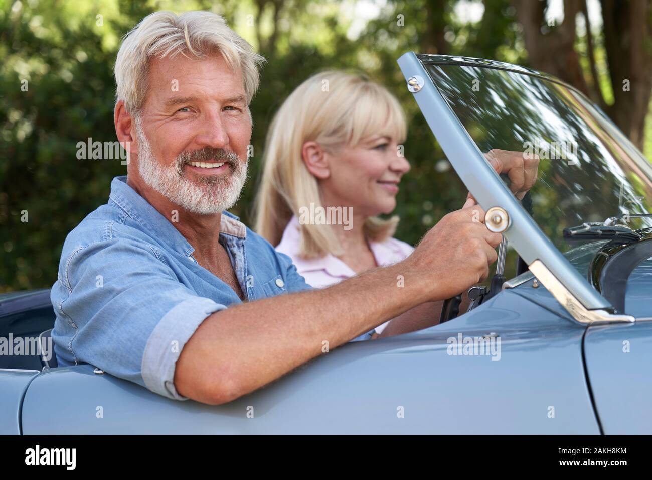 Pareja madura disfrutando de viaje por carretera en la parte superior abierta clásico coche deportivo juntos Foto de stock