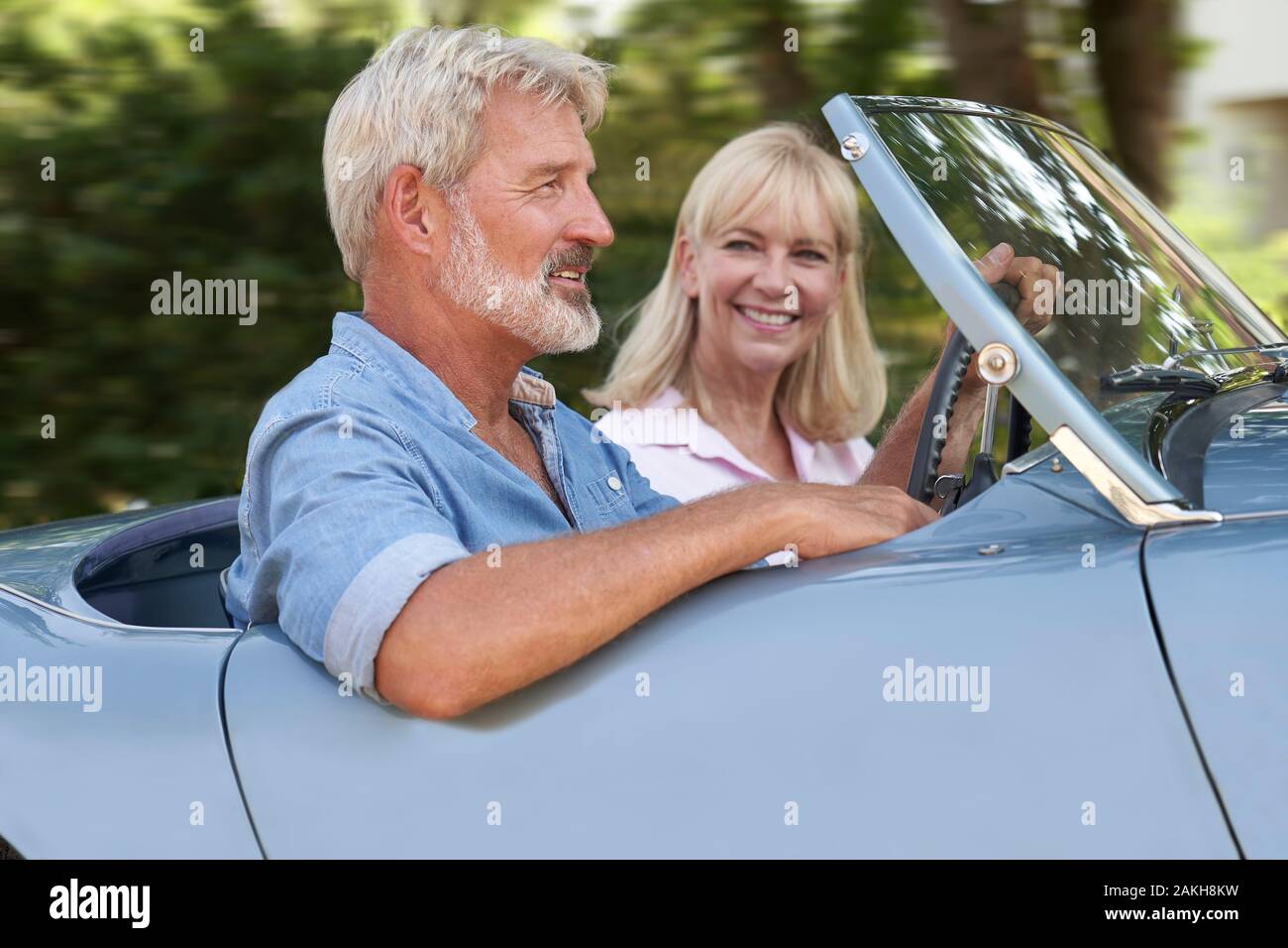 Pareja madura disfrutando de viaje por carretera en la parte superior abierta clásico coche deportivo juntos Foto de stock