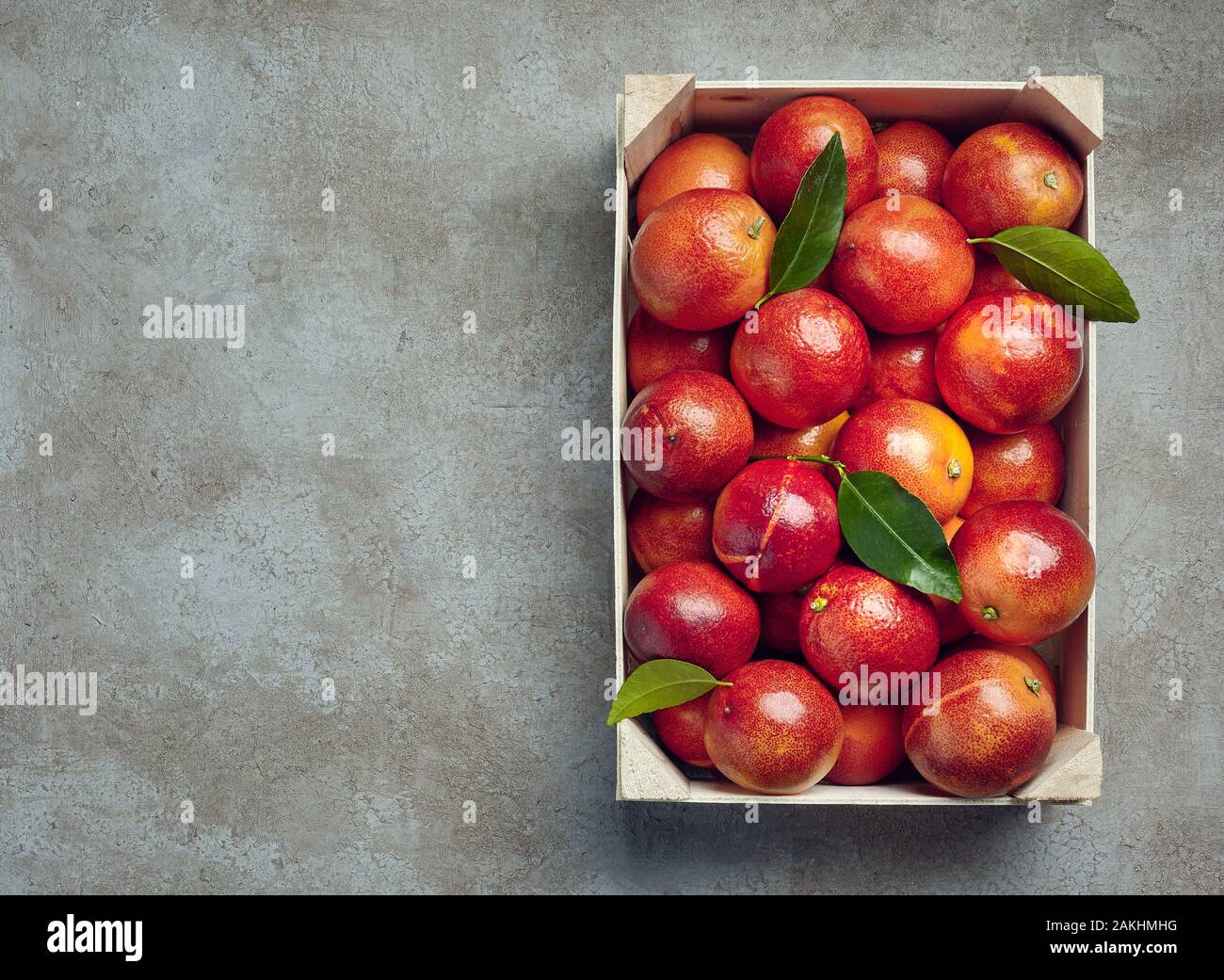 Las naranjas de sangre en una caja de madera sobre un fondo de textura de color gris. Foto de stock