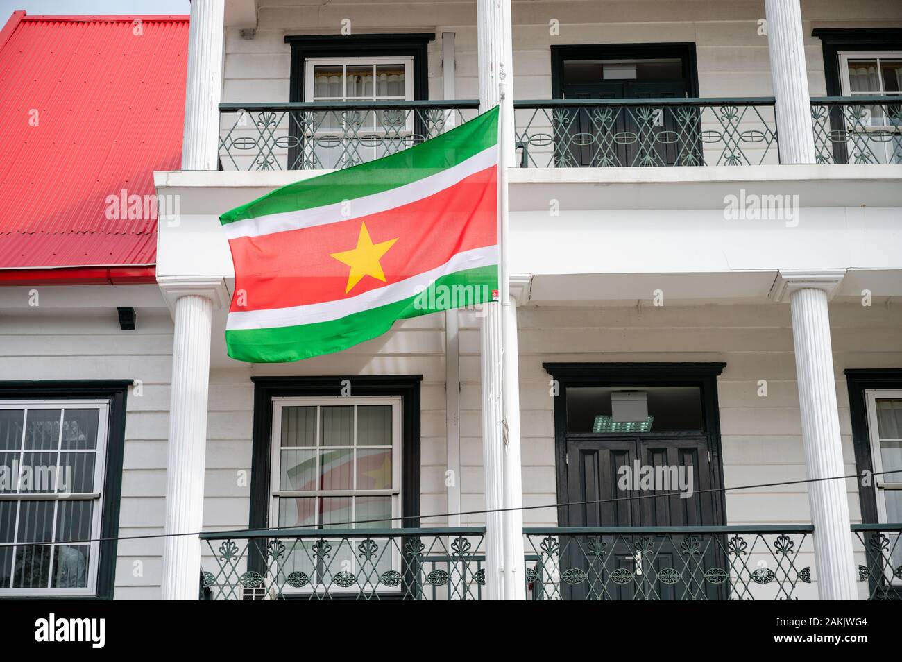 Bandera nacional de Suriname volando fuera de un edificio en Canal Street, en la ciudad capital de Paramaribo, en este pequeño país sudamericano Foto de stock