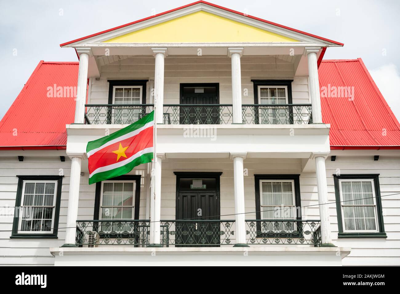 Bandera nacional de Suriname volando fuera de un edificio en Canal Street, en la ciudad capital de Paramaribo, en este pequeño país sudamericano Foto de stock
