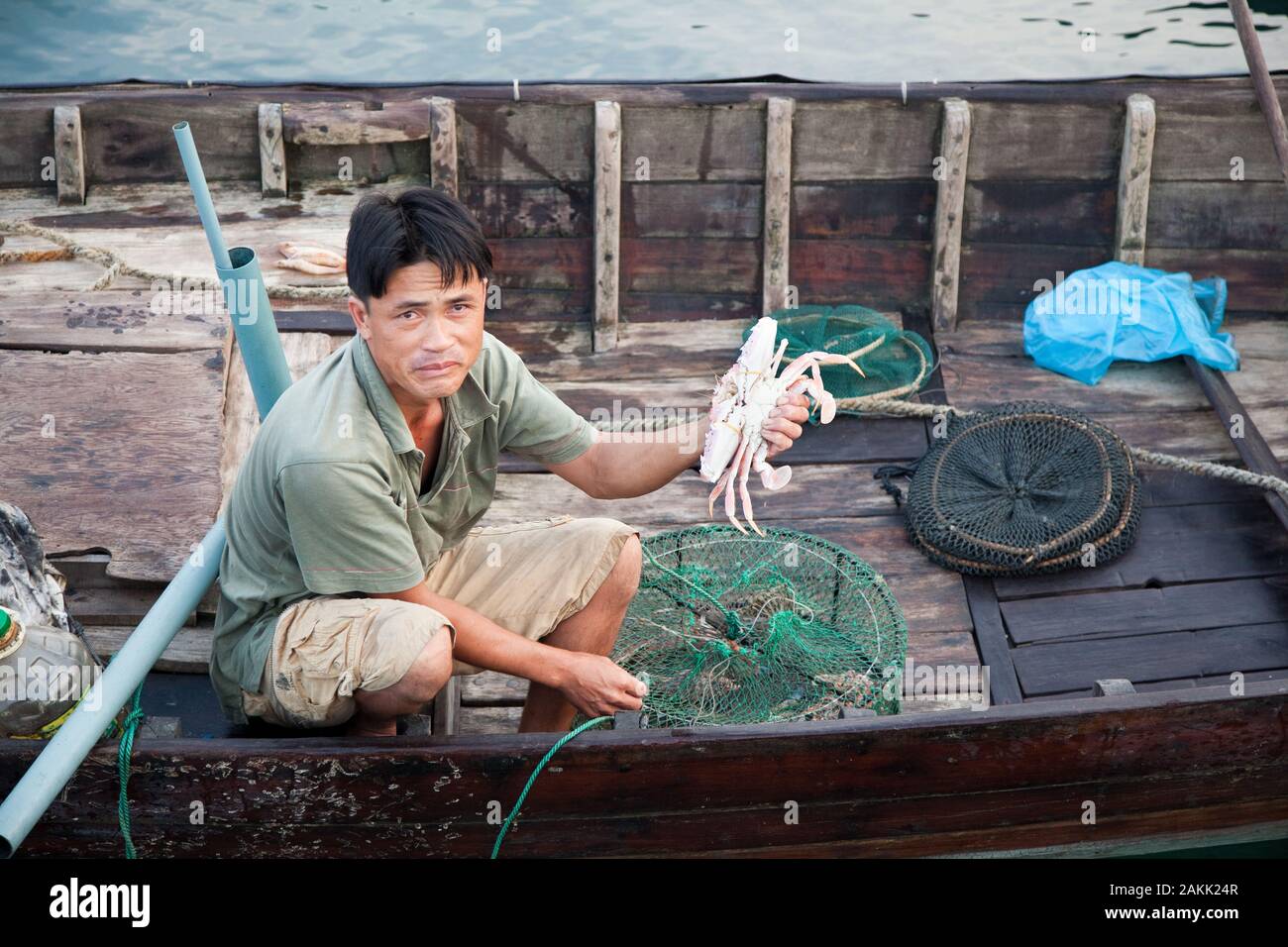 Pescador vietnamita siembra un cangrejo , la pesca del día, es mantener la red fuera del barco en el que la captura en vivo se mantiene hasta el aterrizaje. Foto de stock