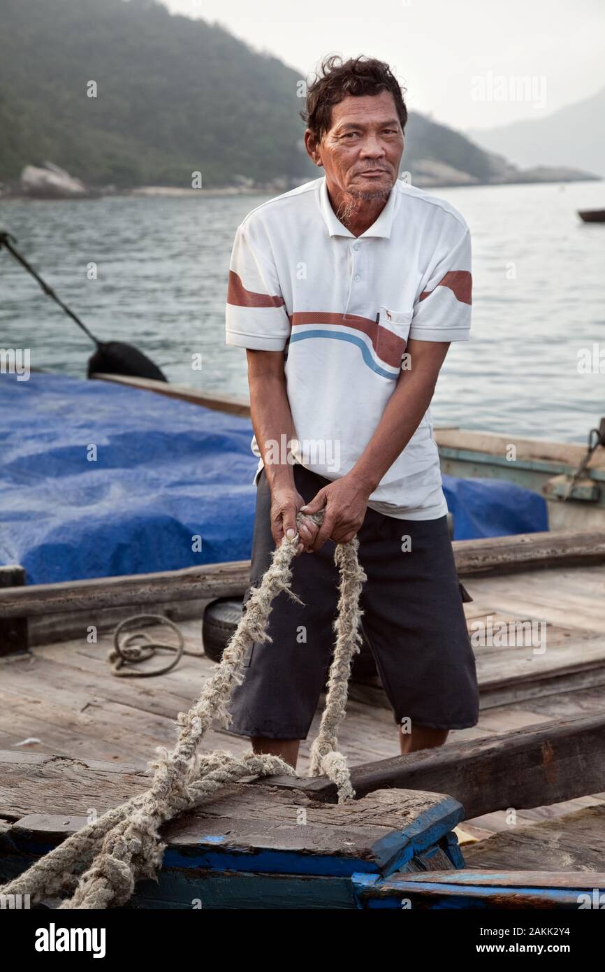 Dock Worker asegura el barco con una cuerda resistente en el muelle Foto de stock