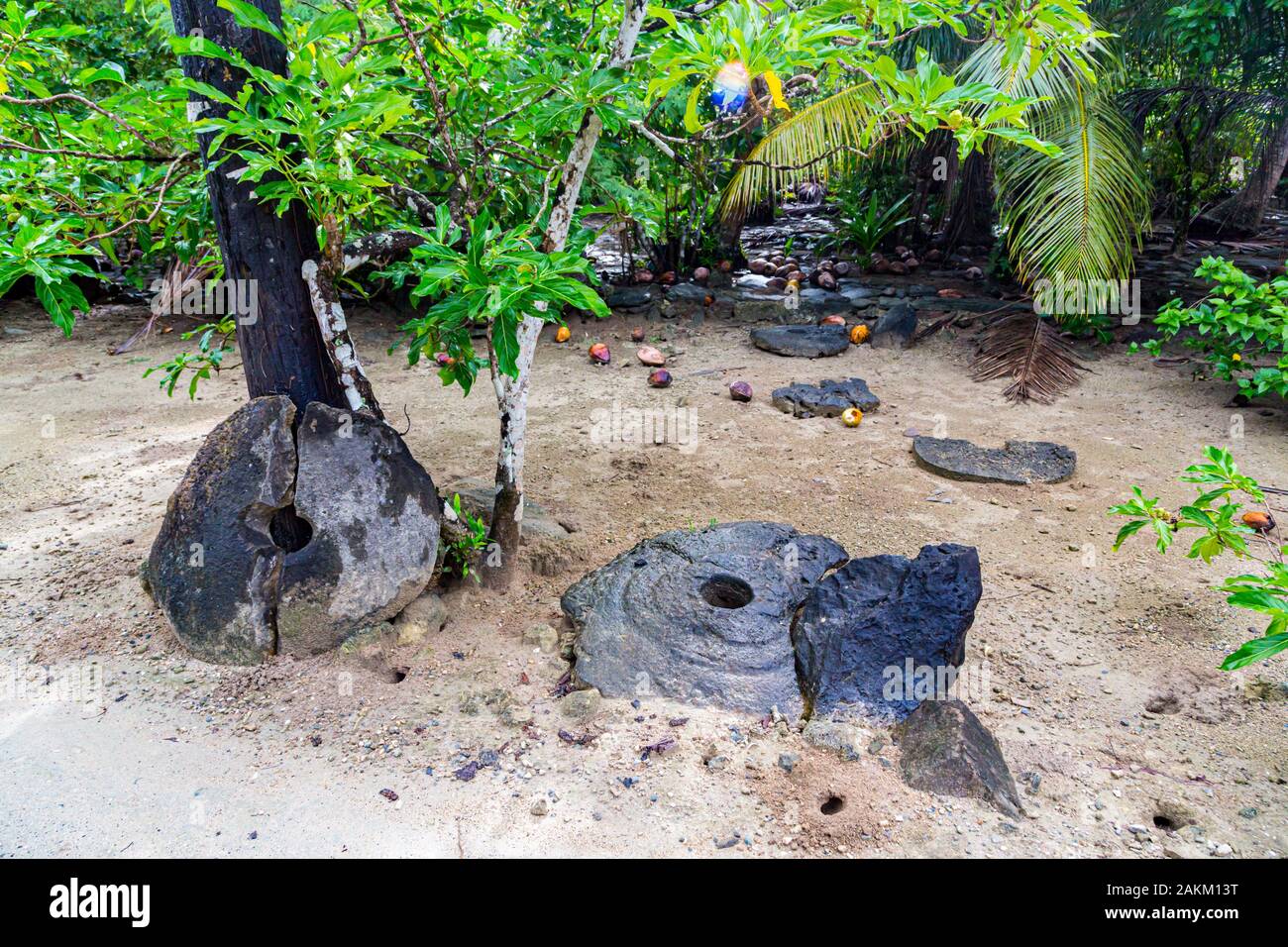 Dos gigantes de piedra megalítico prehistórico rotos, monedas o dinero rai, tumbado en la arena ocultos bajo los árboles de la selva. La Isla Yap, Estados Federados de MICR Foto de stock