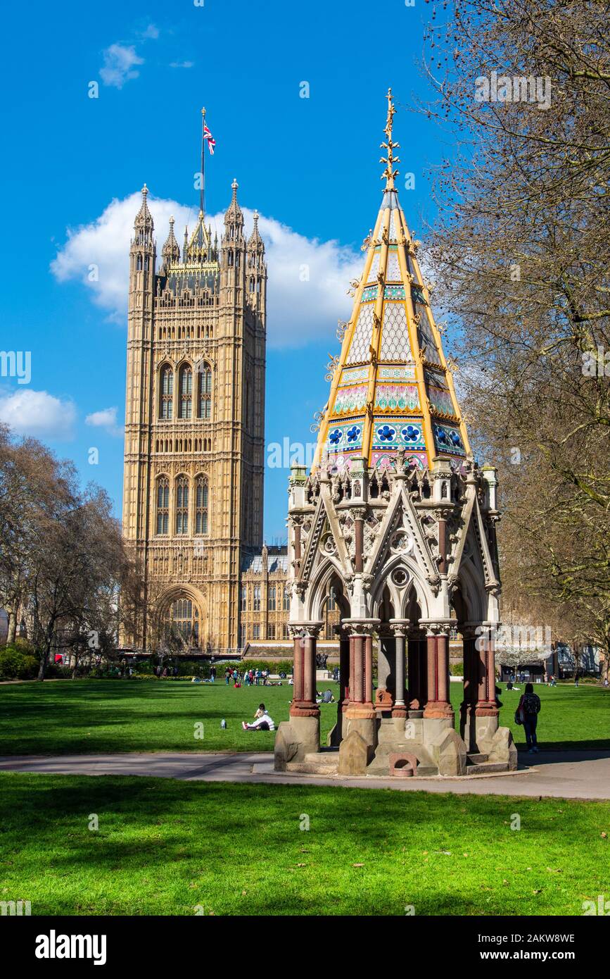 Londres, Reino Unido - 24Mar2019: La fuente conmemorativa de Victorial Buston y torre del palacio de Westminster. Visto desde Victoria Tower Gardens. Foto de stock
