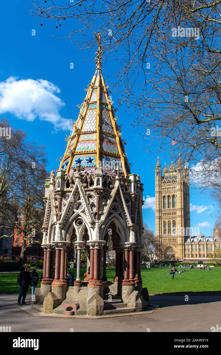 Londres, Reino Unido - 24Mar2019: La fuente conmemorativa de Victorial Buston y torre del palacio de Westminster. Visto desde Victoria Tower Gardens. Foto de stock