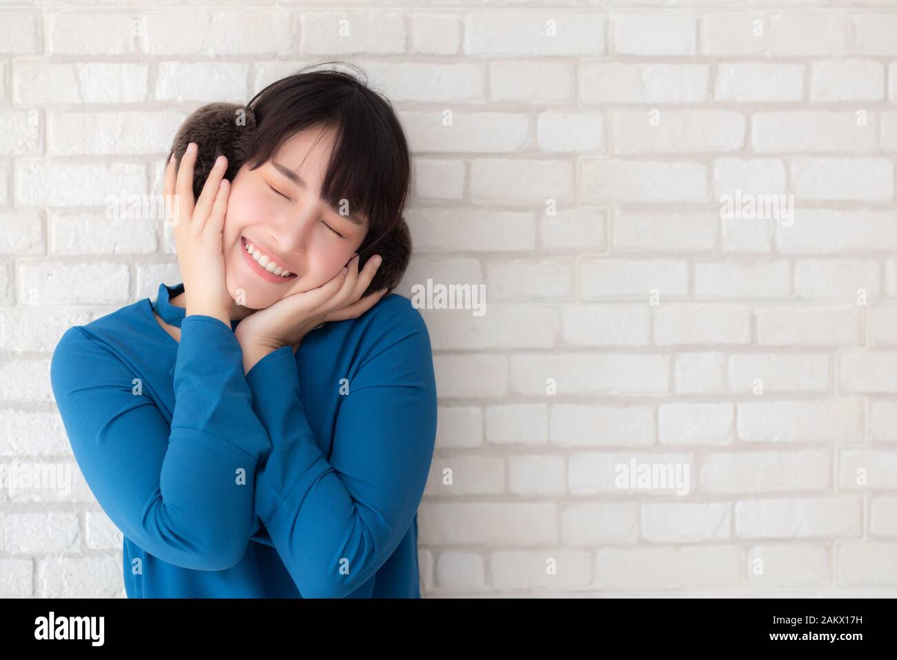 Retrato de joven y bella mujer asiática disfrute y felicidad de pie en el cemento gris textura grunge pared de ladrillos de fondo, es una chica sonriente y cheerf Foto de stock