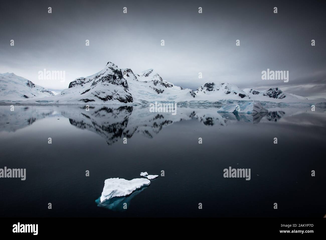 Glaciar hielo, hielo de ladrillo, icebergs frente a las montañas y glaciares de la bahía del Paraíso con reflejos oceánicos sobreatmosféricos, Antártida Foto de stock