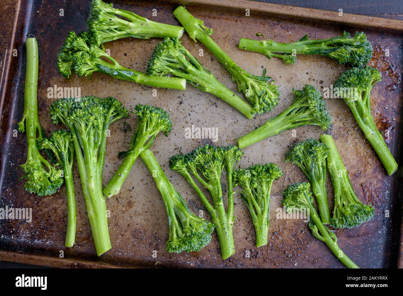 Broccolini crudo Salteado con aceite de oliva en una hoja Pan: Broccolini crudo salteado en aceite de oliva y condimentado con sal y pimienta Foto de stock
