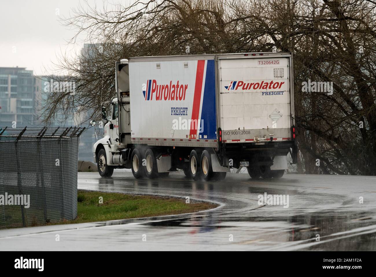 Un camión Purolator conduce a lo largo de una carretera empapada de lluvia, Richmond, B.C., 15 de marzo de 2017. Foto de stock