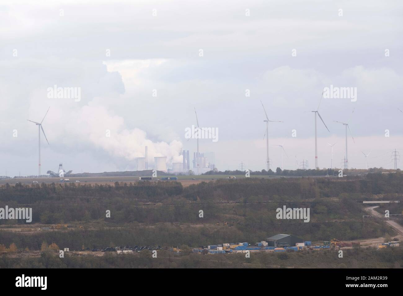 Mina de carbón a cielo abierto, turbinas eólicas y chimeneas de fábrica por autopista, Garzweiller, Alemania Foto de stock
