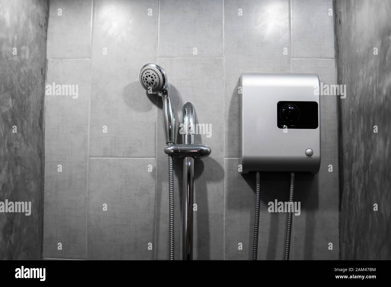 Instant tankless calentador de agua eléctrico instalado en mosaico gris  pared con salida de tubo de entrada y salida y elcb disyuntor de seguridad  sistema de plata y ducha Fotografía de stock 