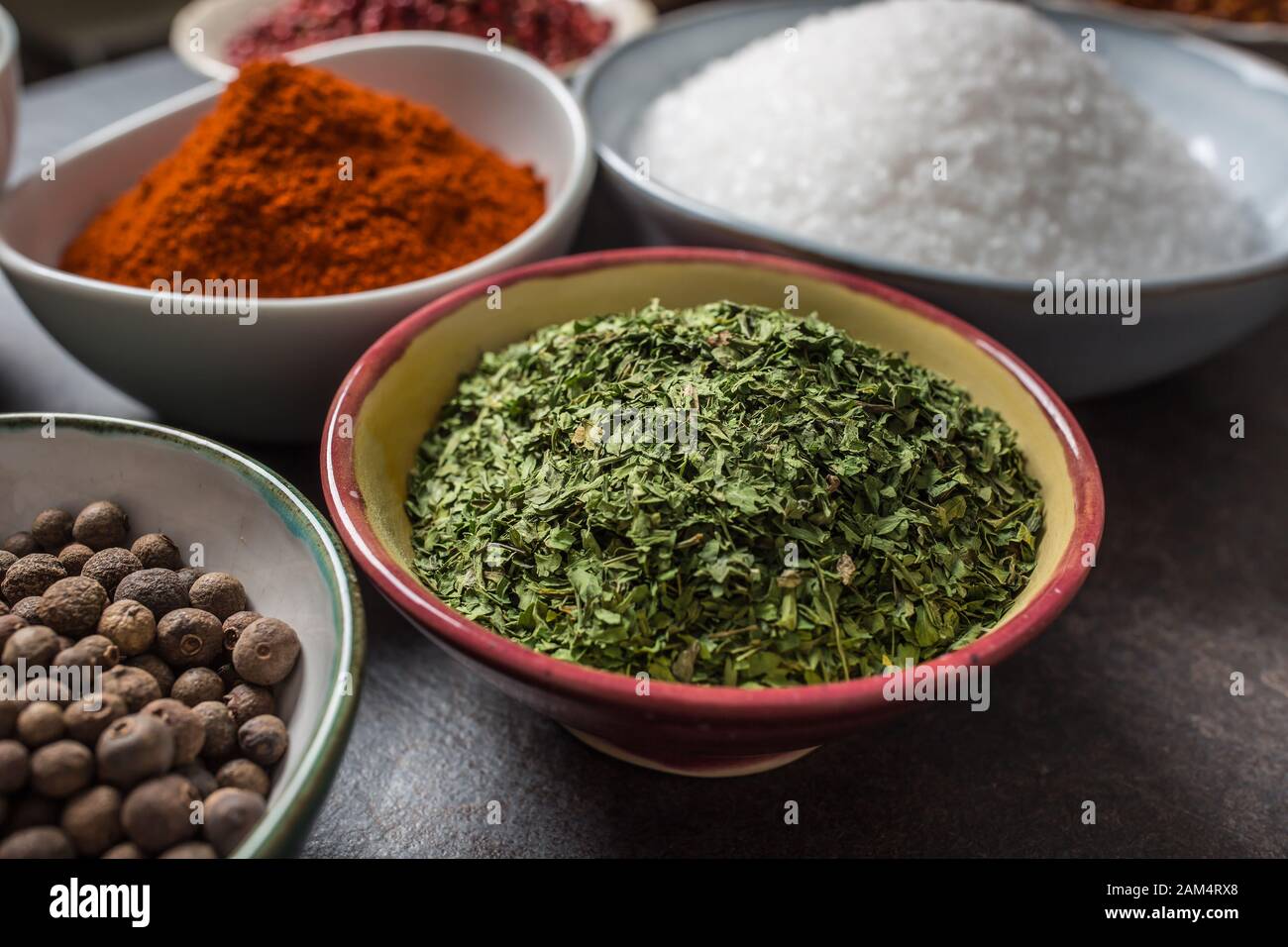 Perejil seco y especias variadas y hierbas en tazones Foto de stock