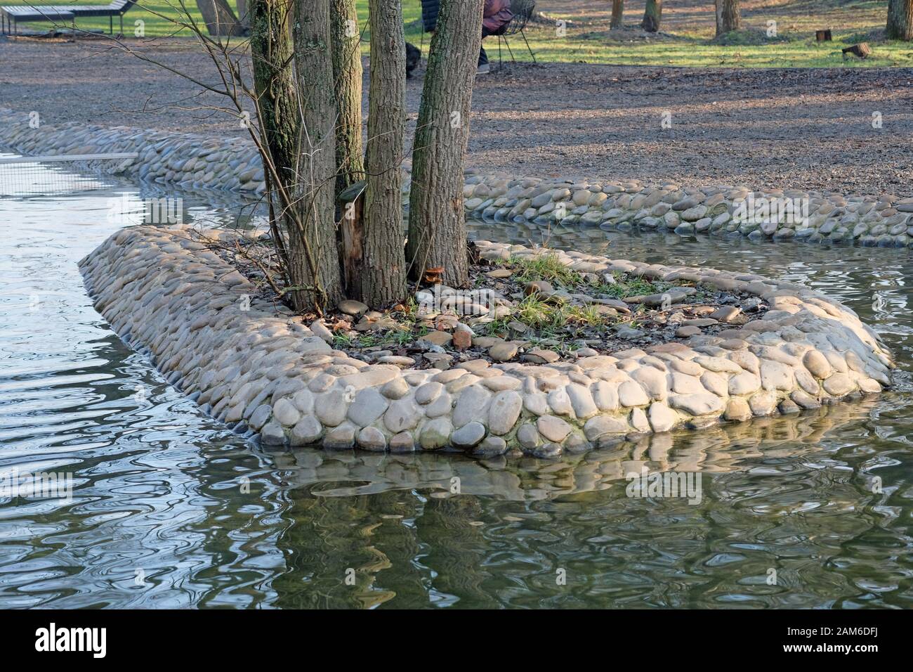 Paisaje del parque de la ciudad. Haciendo un estanque artificial. Las  piedras se ponen alrededor de los árboles en el agua Fotografía de stock -  Alamy